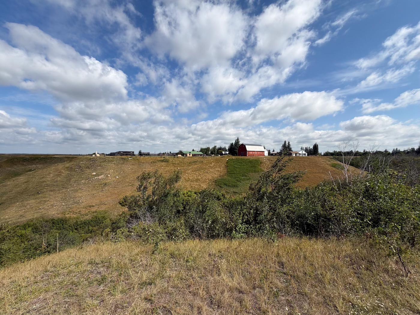 The ranch buildings on the hilltop, seen across the grass