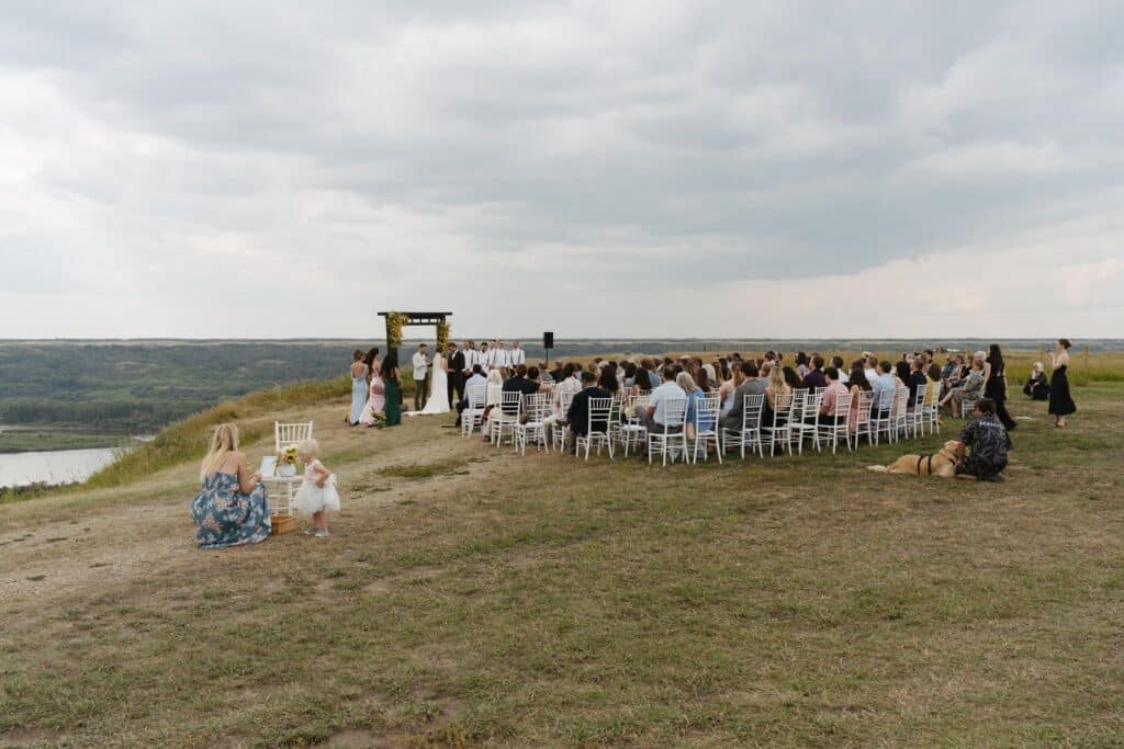 A wedding ceremony on the prairie at Blue Sky Ranch, guests seated in front of a timber arbour