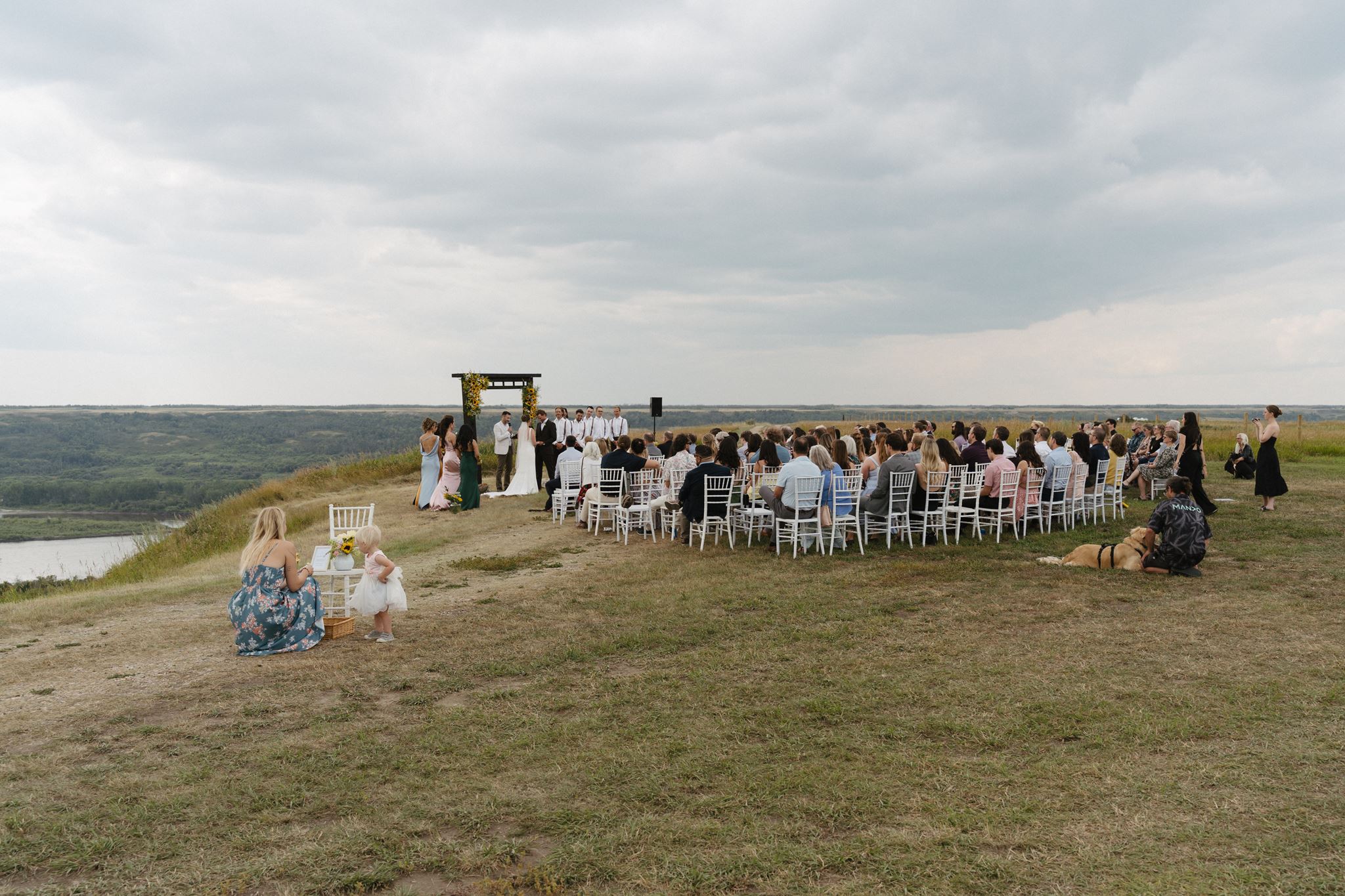 A wedding ceremony on the river hills at Blue Sky Ranch, guests seated under a wide prairie sky