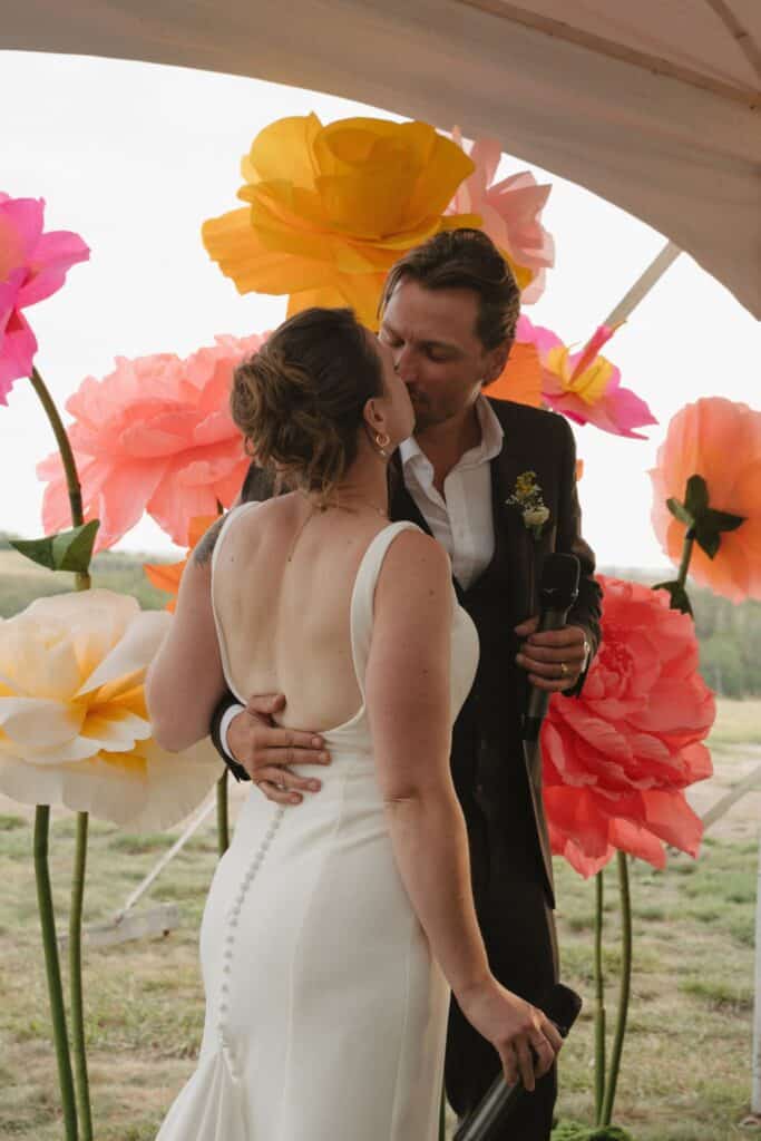 A couple dance under the tent among paper flowers, Blue Sky Ranch wedding