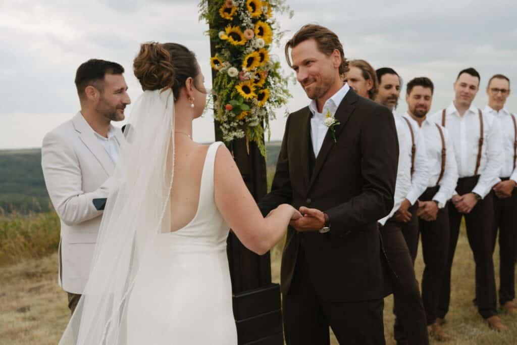 A couple exchange vows under a sunflower-covered arbour, Blue Sky Ranch wedding