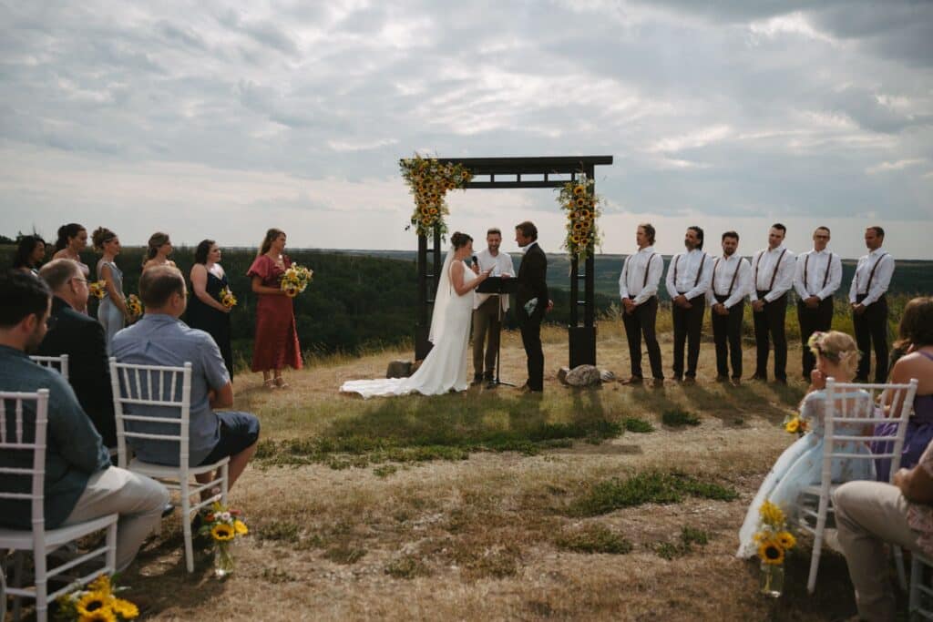 A wedding ceremony on the prairie at Blue Sky Ranch, guests seated in front of a timber arbour