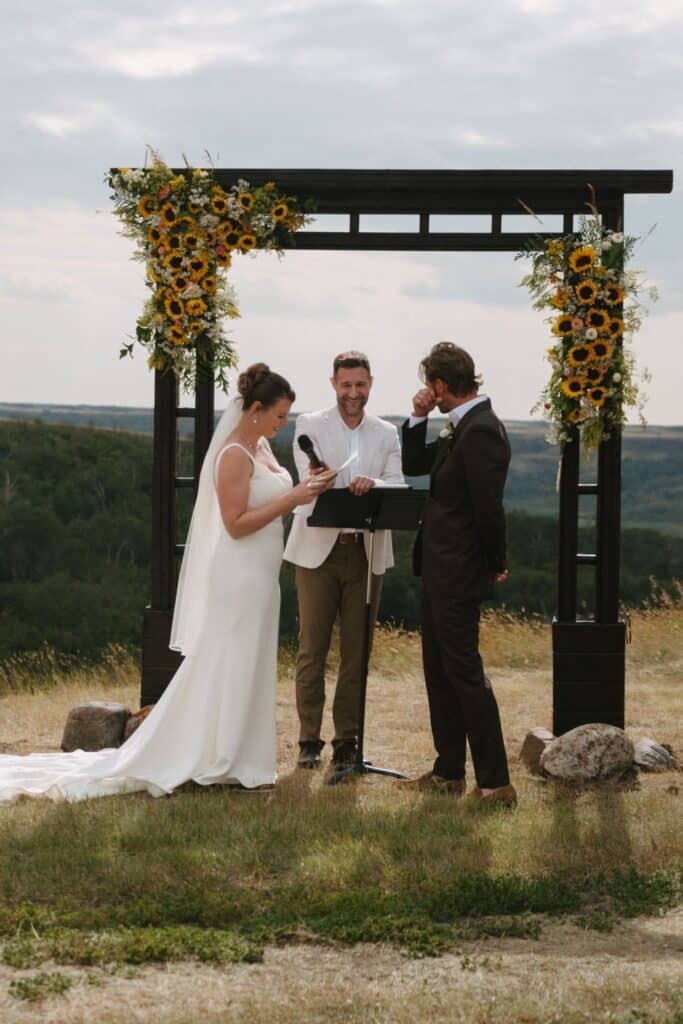 A wedding ceremony on the prairie at Blue Sky Ranch, guests seated in front of a timber arbour