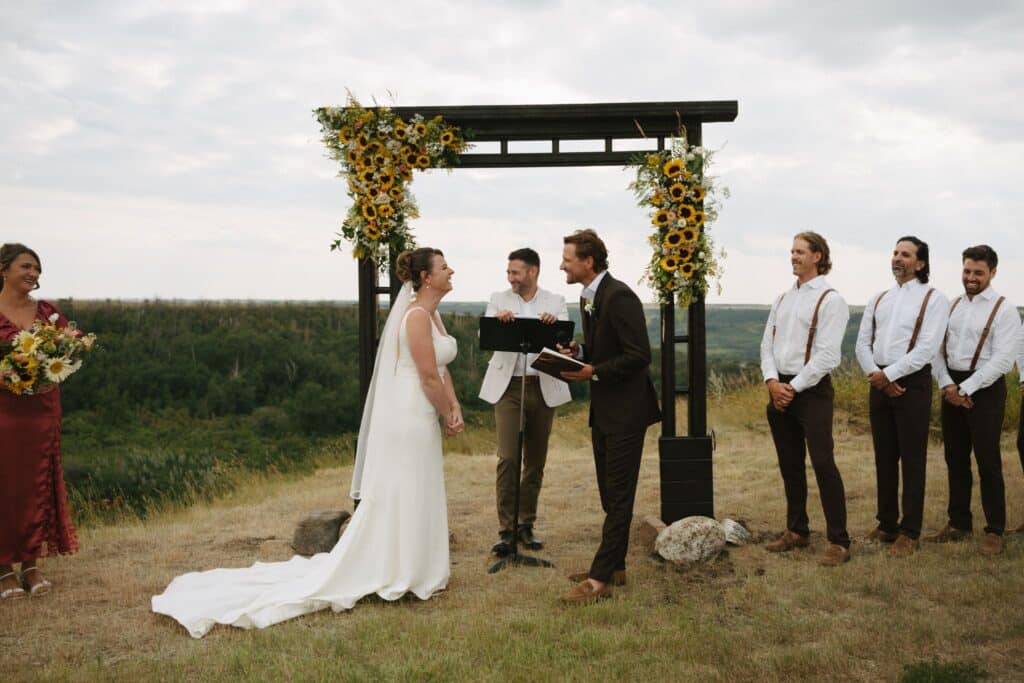 A wedding ceremony on the prairie at Blue Sky Ranch, guests seated in front of a timber arbour